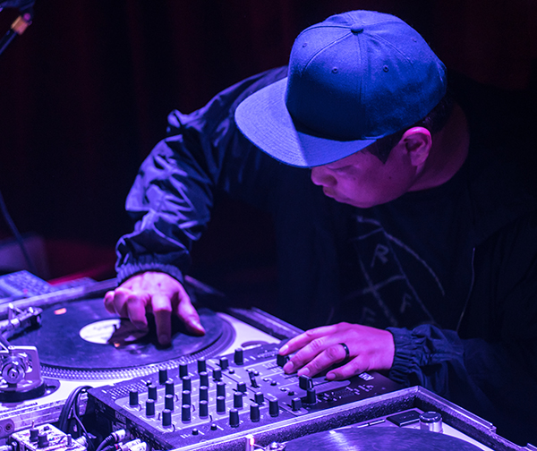 man wearing a cap with his fingers manipulating turntables